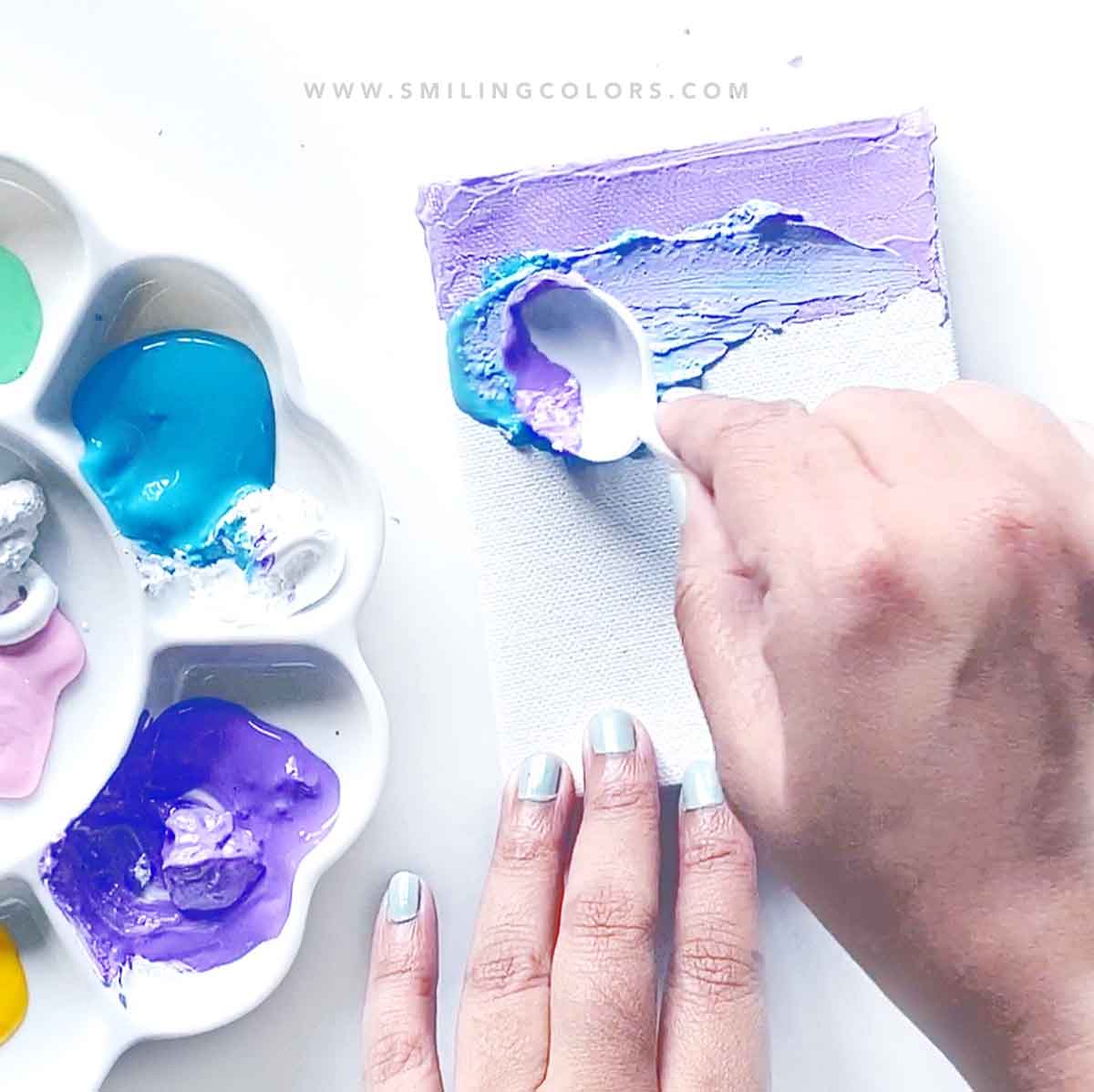 painting with a spoon on a canvas using acrylic paints